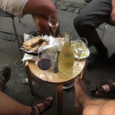 three people sitting at a table with wine and food