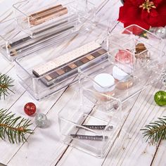 three clear acrylic containers with christmas decorations and makeup on them, one is empty