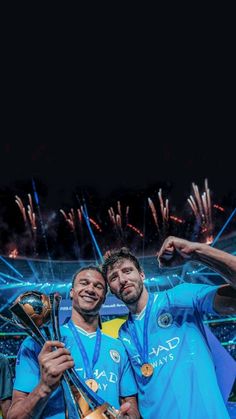 two men holding trophies in their hands while standing next to each other with fireworks behind them