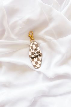 a keychain that is laying on top of a white sheet with a checkerboard design