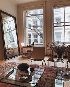 a living room filled with lots of windows next to a table and chairs in front of large windows