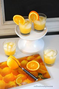 there are oranges on the table with glasses and a tray that has an orange slice in it