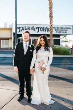 a bride and groom pose for a photo in front of the town sign