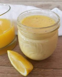 a glass jar filled with yellow liquid next to a sliced lemon on a wooden table