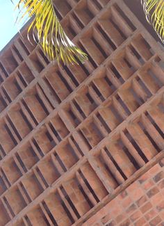 a clock on the side of a brick building with palm trees in the foreground