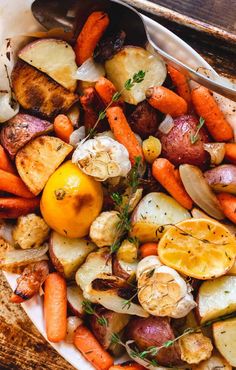 a white plate topped with potatoes, carrots and lemon