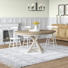 a dining table with four chairs and a rug on the floor in front of it