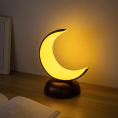 a lamp that looks like the moon is on top of a table next to an open book