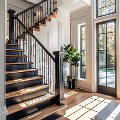 an entryway with stairs and potted plant in the center next to glass doors