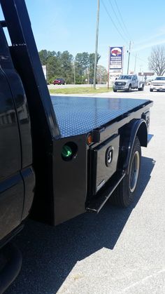 the back end of a black truck parked in a parking lot