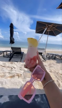 a person holding up a drink on the beach