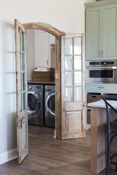 an open door leading to a washer and dryer in a room with wood floors