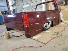 a red pick up truck parked in a garage next to a roll of paper on the floor