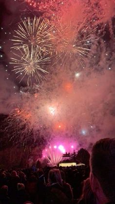 fireworks are lit up in the night sky above a crowd at an outdoor music festival