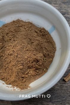 a white bowl filled with brown powder and cinnamon sticks