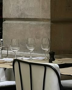 several empty wine glasses sitting on top of a table next to white linen covered chairs