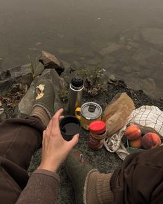 a person sitting on the ground next to some food and water with their feet in the air