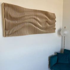 a blue chair sitting in front of a wall mounted art piece with wavy lines on it