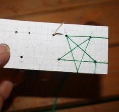 someone is holding up a piece of paper that has been drawn with green thread on it