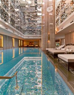 an indoor swimming pool in a hotel with lights on the ceiling and chandeliers hanging from the ceiling