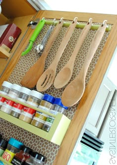 wooden utensils and spoons hanging from hooks on a kitchen cabinet door shelf