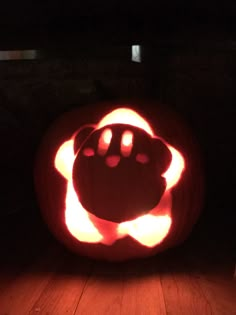 a pumpkin carved to look like an animal's head with glowing eyes and paws