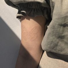 a close up of a person with a butterfly tattoo on their arm and the bottom half of her leg