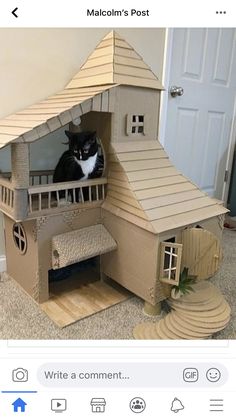 a cat sitting on top of a cardboard house