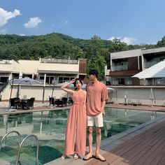 a man and woman standing next to a swimming pool