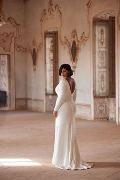 a woman in a white wedding dress standing in an old room with chandeliers