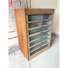 an old wooden cabinet with glass doors on the front and bottom shelves, in a dirty room