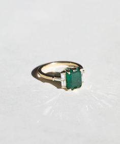 Custom sized in 10-14 days, provided we have it in stock. Please contact us about rush orders. An Emerald cut emerald, with unique black textures, set in a 14k yellow gold setting with invisible set baguette diamonds & tapered baguette diamond accents. Specifications: Approx 2.5ct natural emerald, Approx 0.4ct diamonds in 14k yellow gold. Please note emerald texture and weight may vary slightly from photo, each emerald has its own unique color variation Please contact us for other metal colors a Natural Emerald Engagement Ring, Timeless Emerald Diamond Ring In Yellow Gold, Timeless Yellow Gold Diamond Ring With Emerald, Timeless Rectangular Yellow Gold Emerald Ring, Timeless Emerald Ring With Baguette Diamonds For Anniversary, Octagon Emerald Ring In Yellow Gold With Diamond, Classic Yellow Gold Emerald Ring With Baguette Diamonds, Elegant Emerald Ring In Yellow Gold With Baguette Diamonds, Elegant Emerald Ring With Baguette Diamonds In Yellow Gold