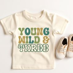 a t - shirt with the words young wild and three written in green on it