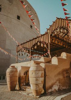 several large vases on display in front of a building with flags hanging from the roof