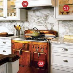 a kitchen with white cabinets and marble counter tops, including an old - fashioned stove