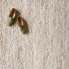 two pairs of green shoes sitting on top of a carpet