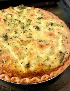 a quiche with cheese and broccoli on it sitting in an open oven