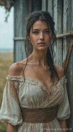 a woman in a white dress standing next to a wooden structure and looking at the camera