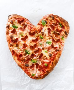 a heart shaped pizza sitting on top of a piece of paper