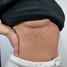 a woman's stomach with a leaf tattoo on her belly and the bottom part of her lower body