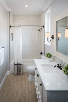 a bathroom with white fixtures and wood flooring