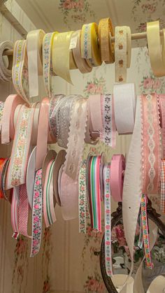 many different colored ribbons are hanging on a rack in a room with floral wallpaper