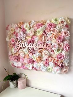 a pink and white flower wall with the word gorgeous on it