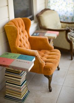 an orange chair sitting next to a stack of books