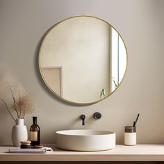 a round mirror on the wall above a white sink in a room with beige walls