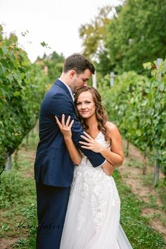 a bride and groom hugging in the vineyard