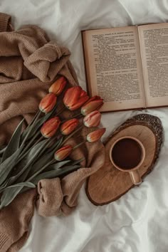 an open book and some flowers on a bed