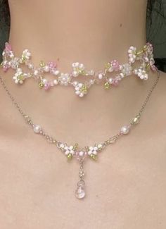 a woman wearing a pink and white necklace with flowers on it's neckline