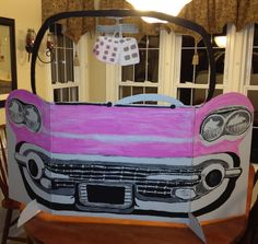 a pink and white car is painted on the side of a table in front of a window