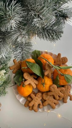 oranges and dog biscuits are on a plate next to a christmas tree